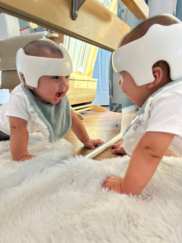 An infant smiling at his reflection in the mirror