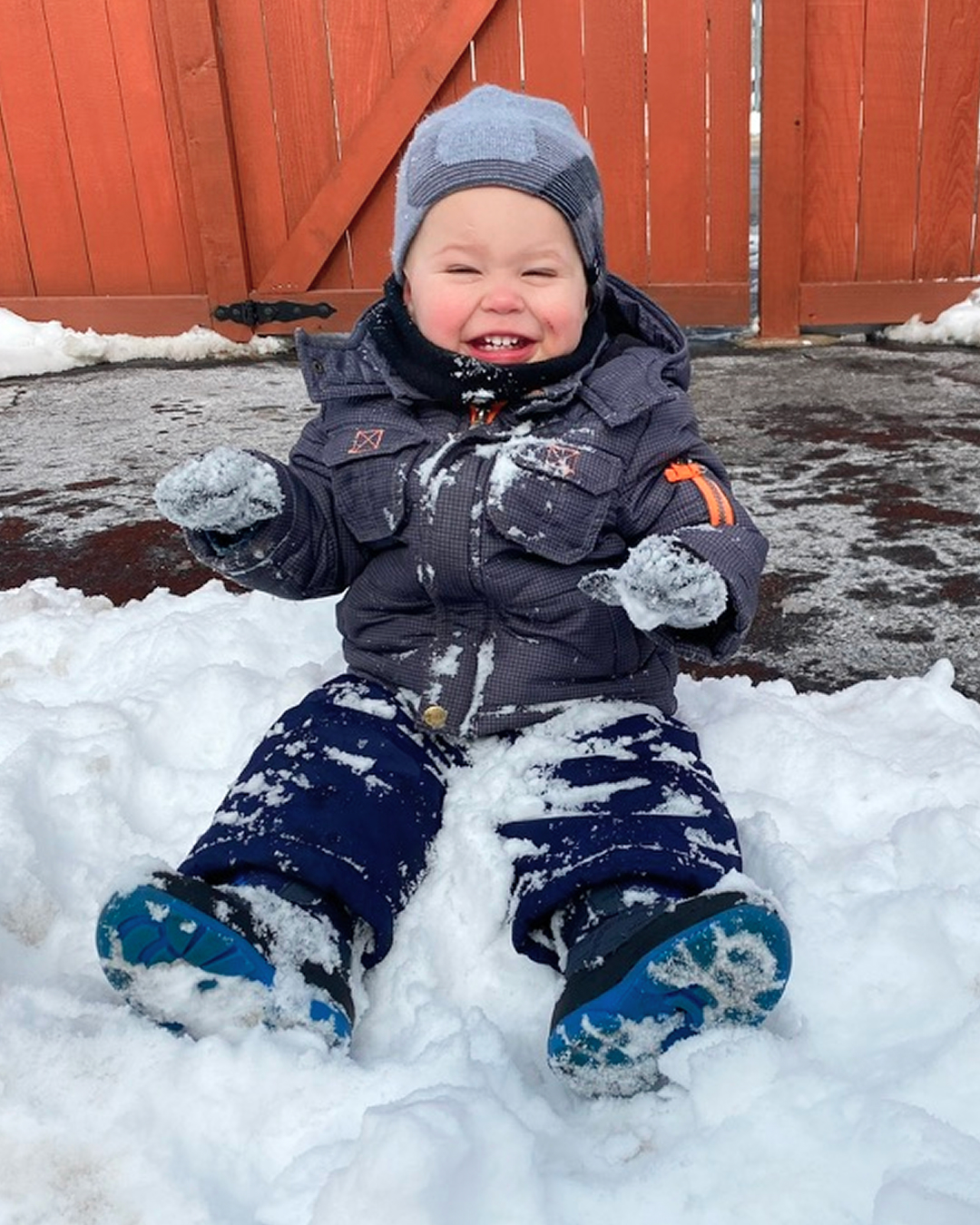A young child in a snowsuit playing in the snow