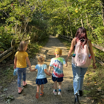 A Montessori guide walking with children along a forest path