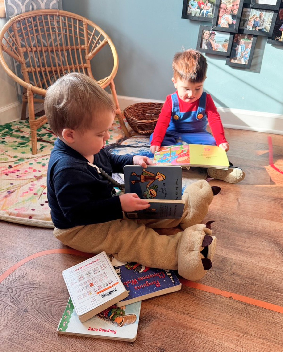 Two young children reading books on the floor