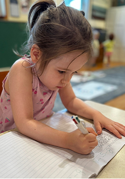 A young girl focused on writing in a notebook