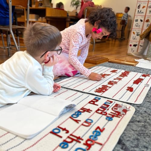 Two children working on a moveable alphabet to create sentences